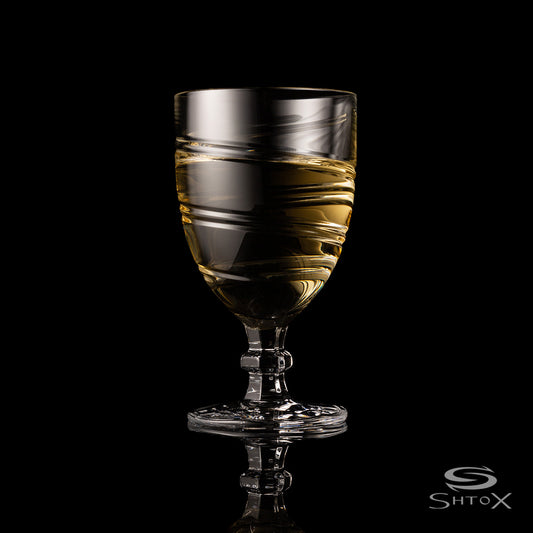 Crystal rotating wine glass with a bold, swirling design, filled with light golden liquid, set against a black background with the Shtox logo at the bottom.