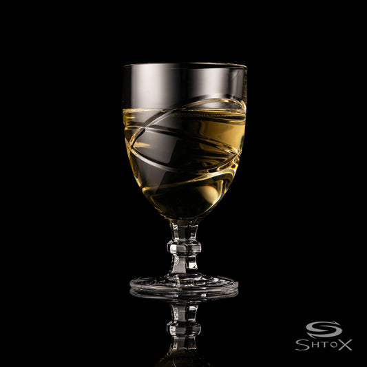 Crystal rotating wine glass with a swirling design, filled with a light golden liquid, set against a black background, featuring the Shtox logo at the bottom