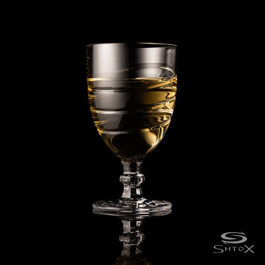 Crystal rotating wine glass with a smooth, swirling design, filled with light golden liquid, set against a black background with the Shtox logo at the bottom.